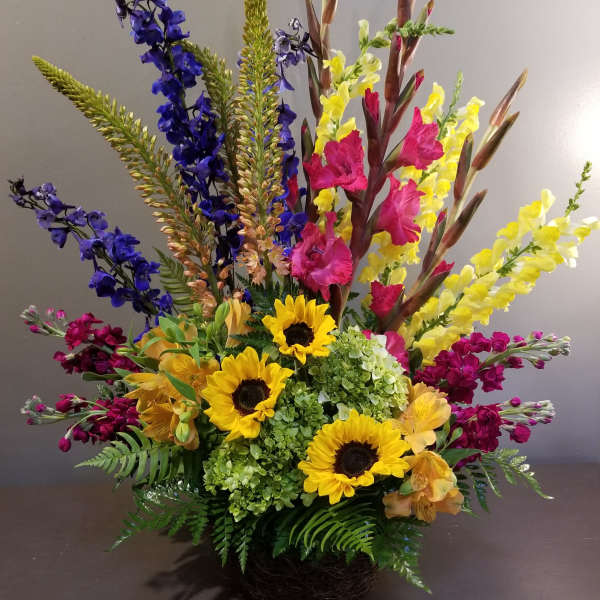 Colorful mixed flower arrangement with sunflowers, snapdragons, and hydrangeas in a basket