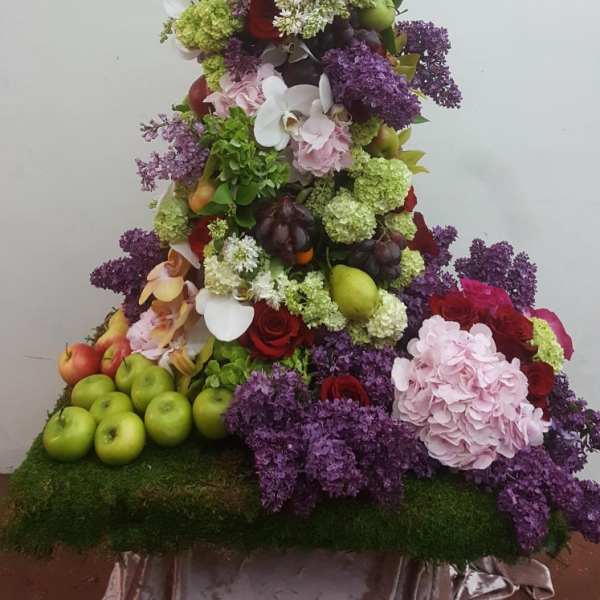 Tiered floral display with fruit, hydrangeas, roses, and orchids
