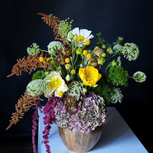 Mixed floral arrangement in a ceramic vase with yellow and white blooms
