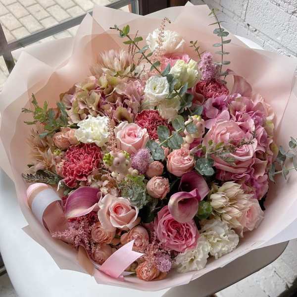 Pink mixed bouquet with roses, hydrangeas, and calla lilies wrapped in pale paper