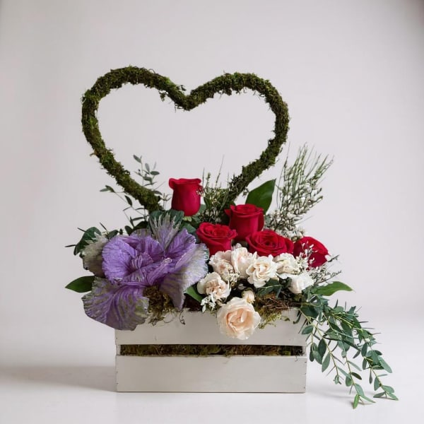 Heart-shaped floral arrangement with red and cream roses in a white box