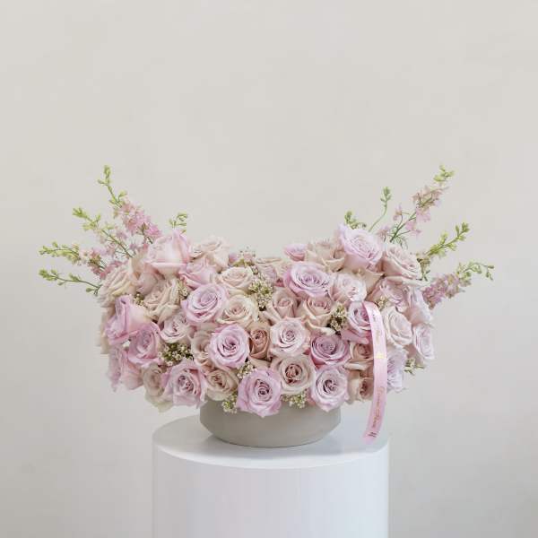 Large pastel pink rose arrangement in a round vase