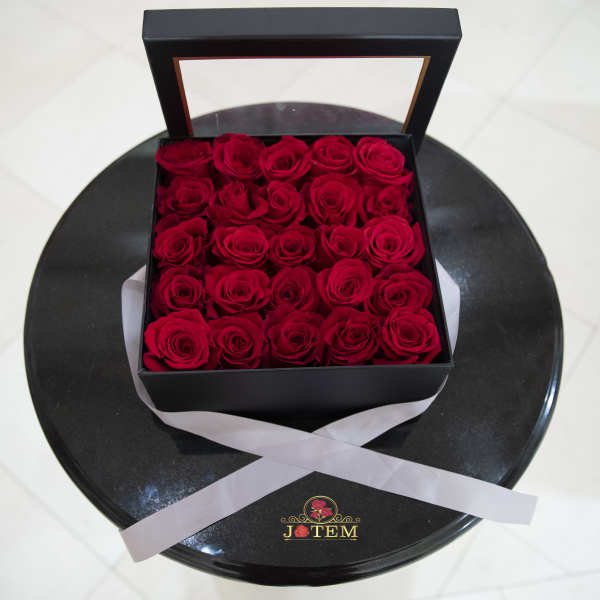 Box of red roses with a clear lid on a round black base