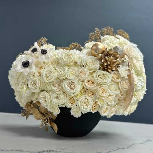 Cream rose bouquet in a black vase with gold ornaments