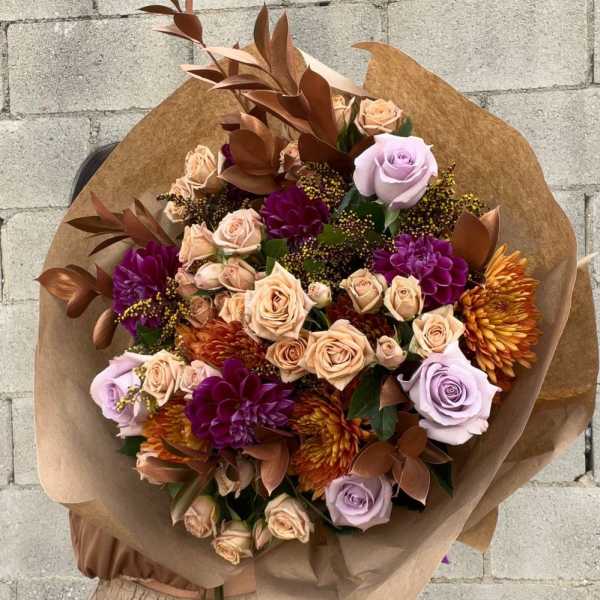 Large bouquet of roses and chrysanthemums wrapped in brown paper