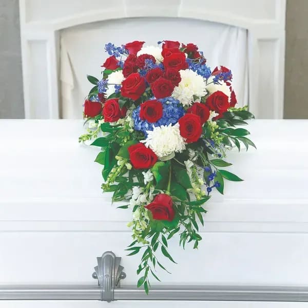 Red roses and white flowers arranged on a white casket