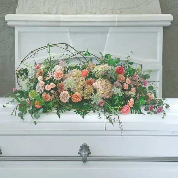 Pastel floral casket spray with roses and greenery
