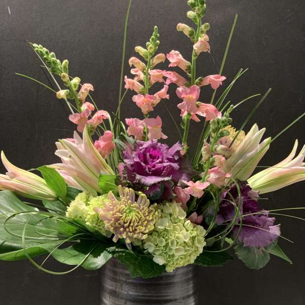 Mixed floral arrangement in a dark vase with pink snapdragons and lilies