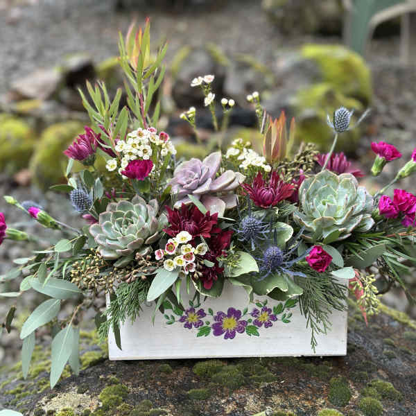 Succulent and magenta flower arrangement in a painted wooden box