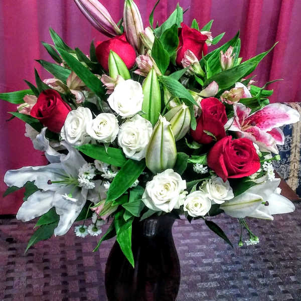 Bouquet of red and white roses with lilies in a black vase