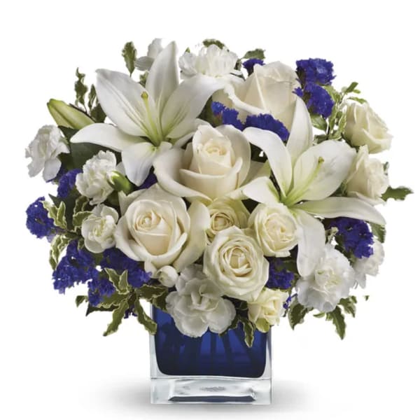 White lilies and roses arranged in a blue glass vase