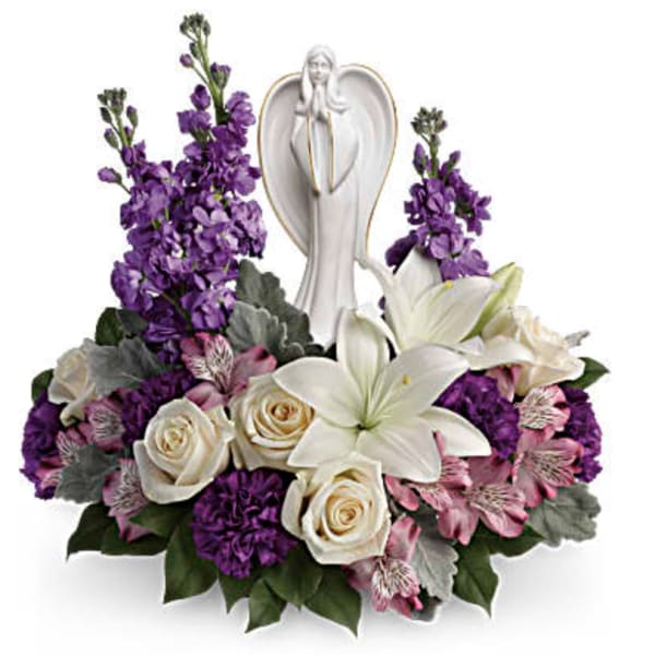 Purple and white floral arrangement with a praying angel figurine