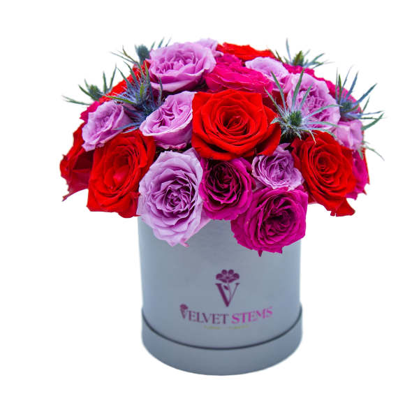 Red and lavender roses arranged in a gray hat box