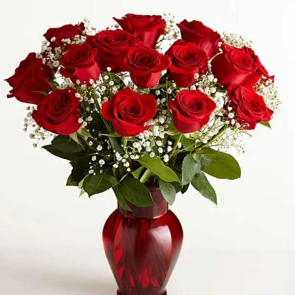 Red roses arranged in a red glass vase with white baby's breath