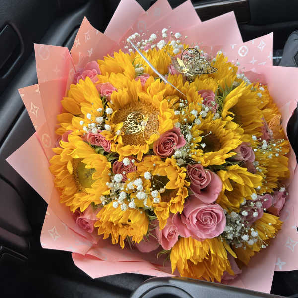 Bouquet of yellow sunflowers and pink roses wrapped in pink paper