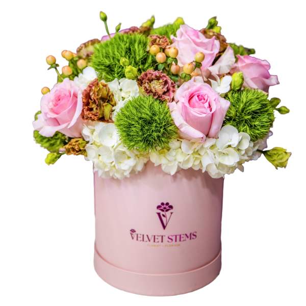 Pink roses and white hydrangeas in a pink hatbox with green pom-pom flowers