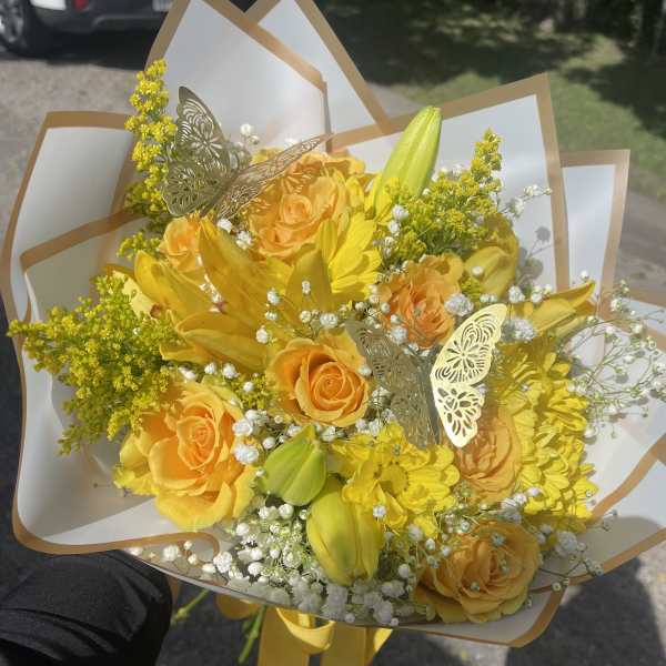 Yellow bouquet with roses, lilies, and daisies wrapped in white paper