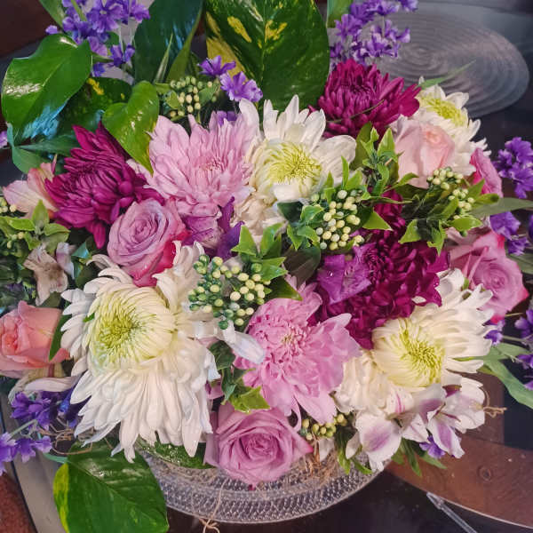 Mixed bouquet of pink, white, and purple flowers in a low container