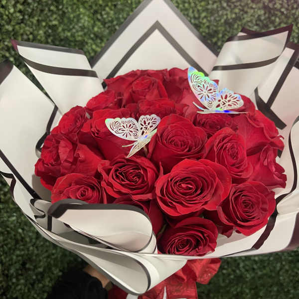 Bouquet of red roses wrapped in white paper with black trim