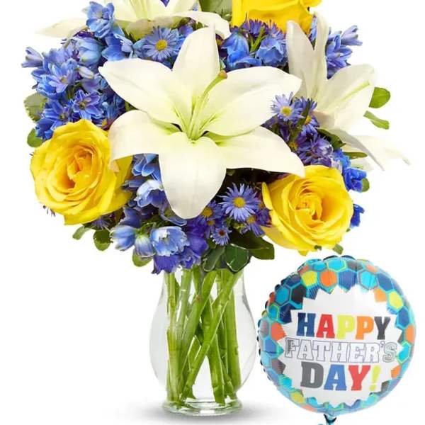 Bouquet of white lilies, yellow roses, and blue flowers in a glass vase with a Father's Day balloon