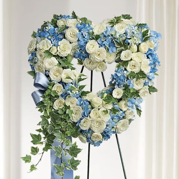Heart-shaped floral wreath of white and blue flowers on a stand