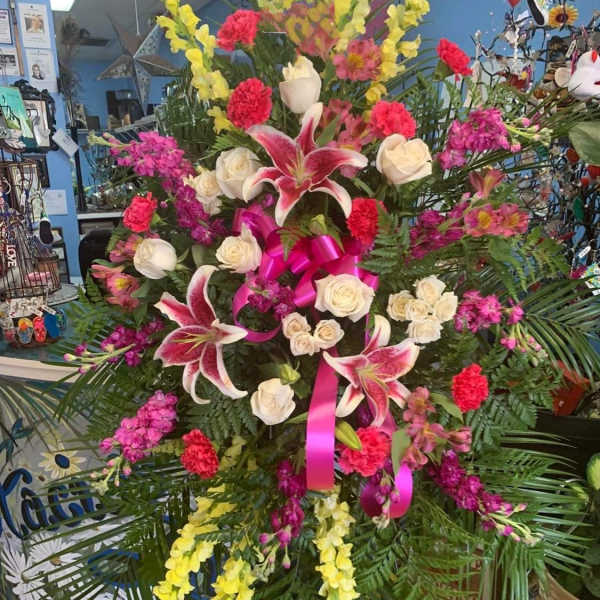 Large standing floral spray with pink lilies, white roses, and yellow blooms