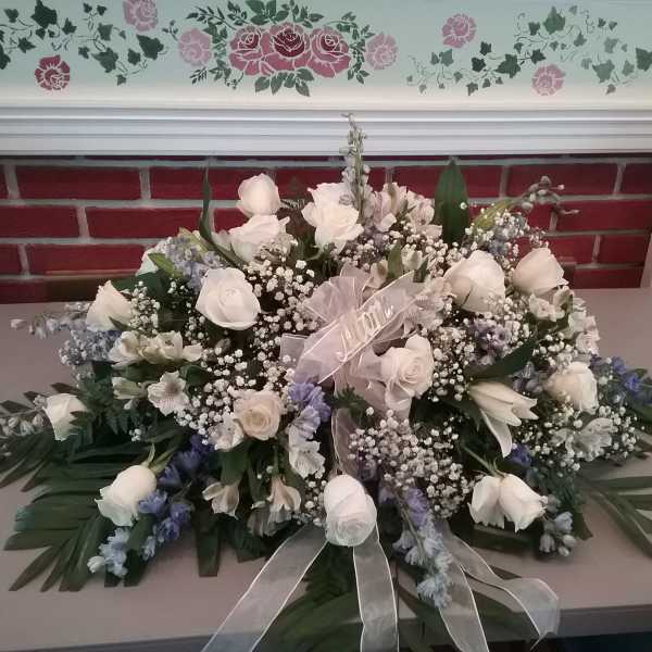 White rose and blue floral arrangement with a sheer ribbon