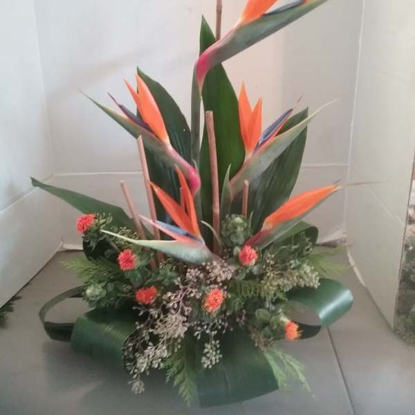 Tropical arrangement with orange bird-of-paradise flowers and small red blooms