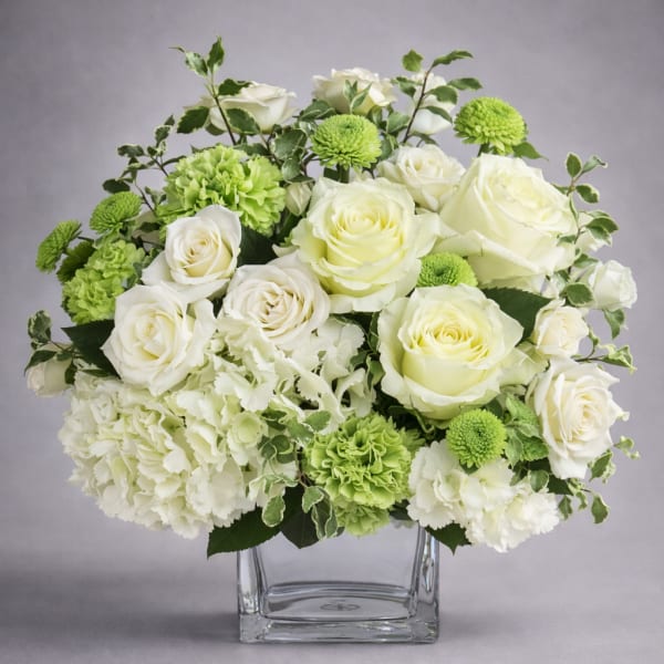 White roses and green carnations in a clear glass vase