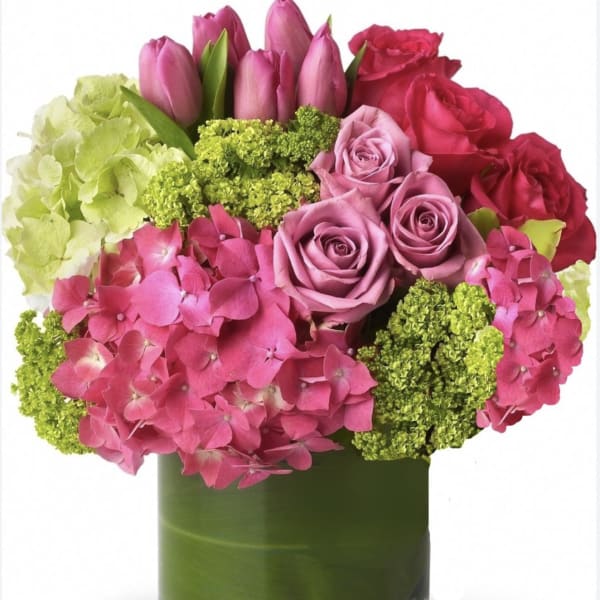 Pink and red roses with hydrangeas and tulips in a green glass vase
