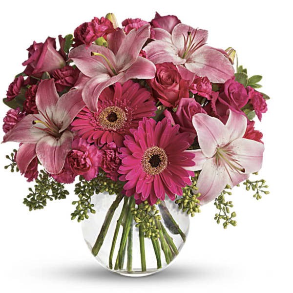 Pink lilies, gerbera daisies, and roses in a clear glass vase