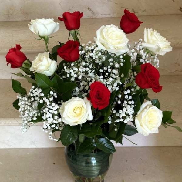 Red and white roses arranged in a glass vase with baby's breath