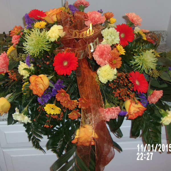 Large mixed floral arrangement with a brown ribbon and "Dad" sign