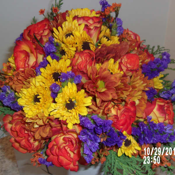 Bright mixed bouquet of red roses, yellow daisies, and purple filler flowers