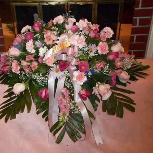 Pink and white floral arrangement with ribbon on a table