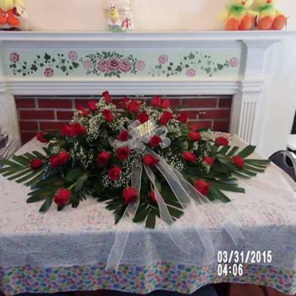 Large red rose arrangement on a table with a sheer ribbon bow