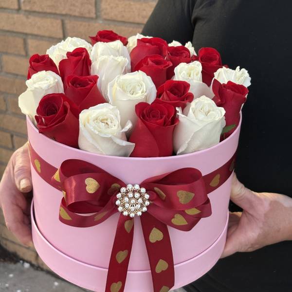 Red and white roses in a pink round box with a heart ribbon