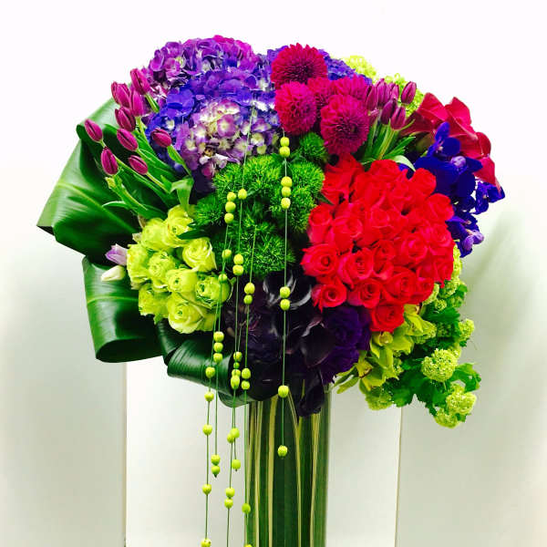 Tall bouquet of multicolored flowers in a glass vase with hanging beads