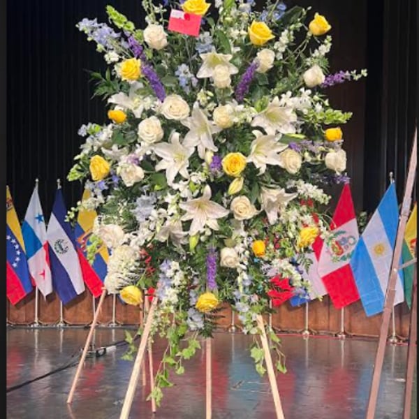 Large standing floral spray with white lilies, yellow roses, and purple flowers