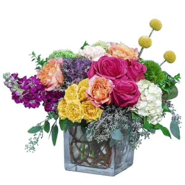 Colorful mixed flower arrangement in a square glass vase