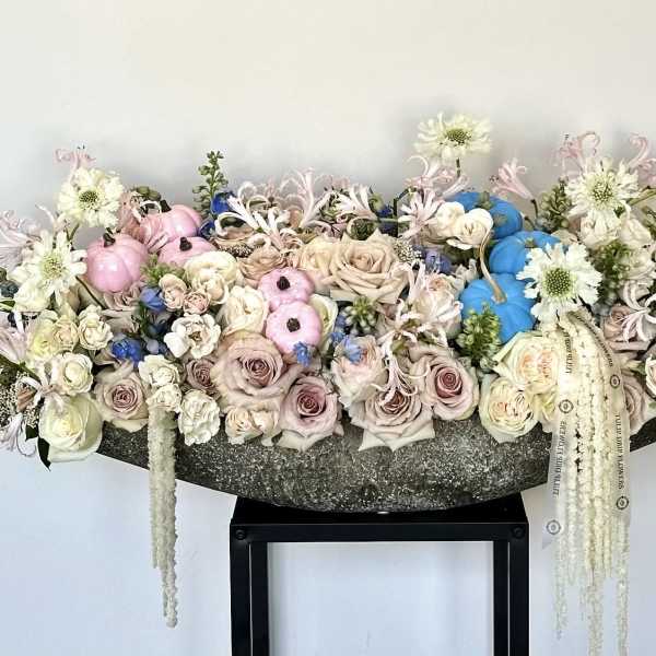 Large pastel floral arrangement with roses, white blooms, and decorative pumpkins