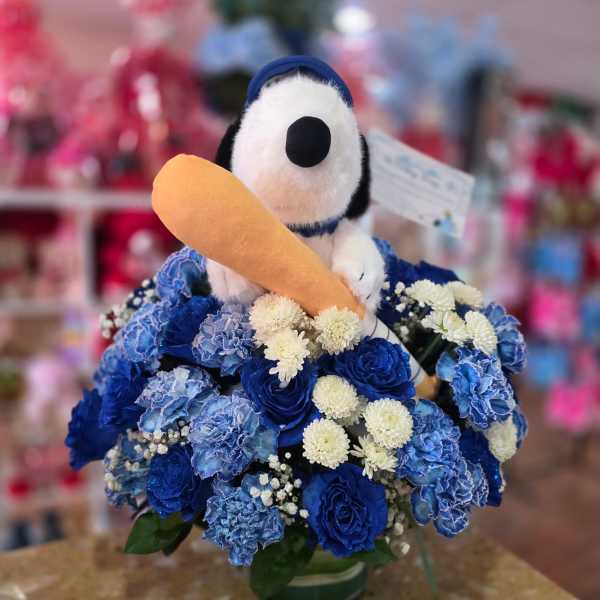 Snoopy plush in a blue flower arrangement holding a toy carrot