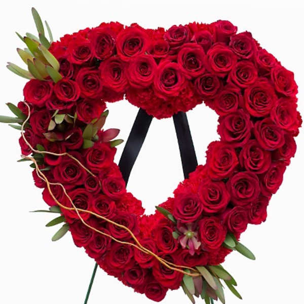Heart-shaped red rose wreath on a stand with small greenery accents