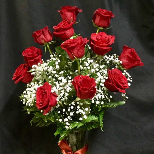 Red roses arranged in a glass vase with white baby's breath