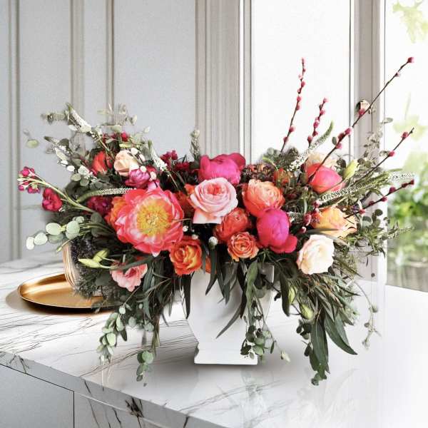 Mixed pink and orange floral arrangement in a white vase