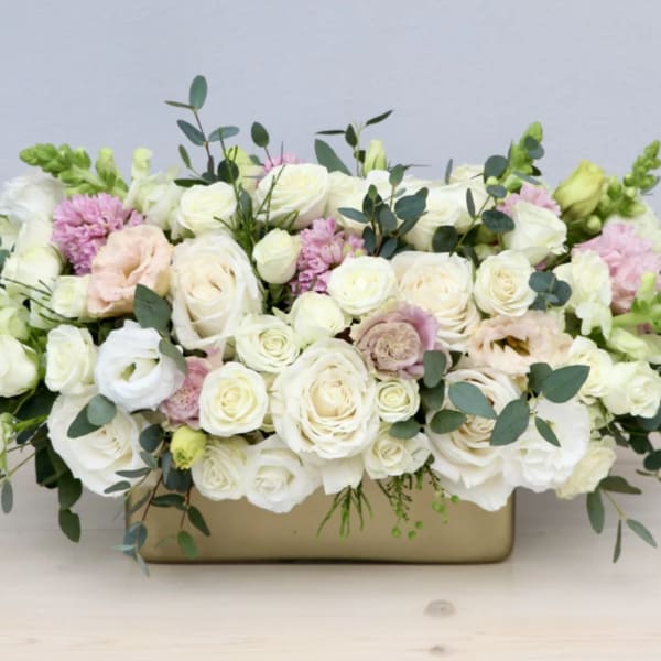 Low floral arrangement of white and blush roses in a rectangular vase