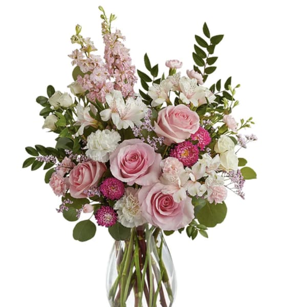 Pink roses and white flowers arranged in a clear glass vase