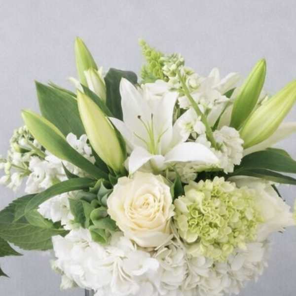 White lilies and roses arranged in a clear glass vase