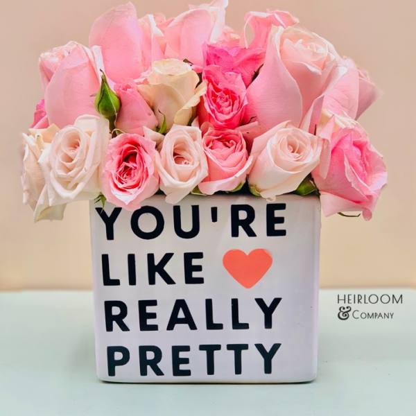 Pink and white roses in a square vase with a printed message