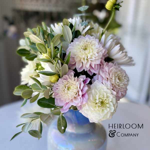 Pink and white flowers arranged in a glass vase with greenery